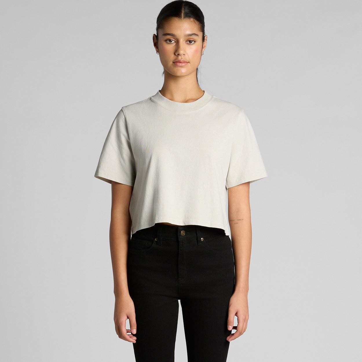 Person wearing a plain white t-shirt and black pants on a gray background