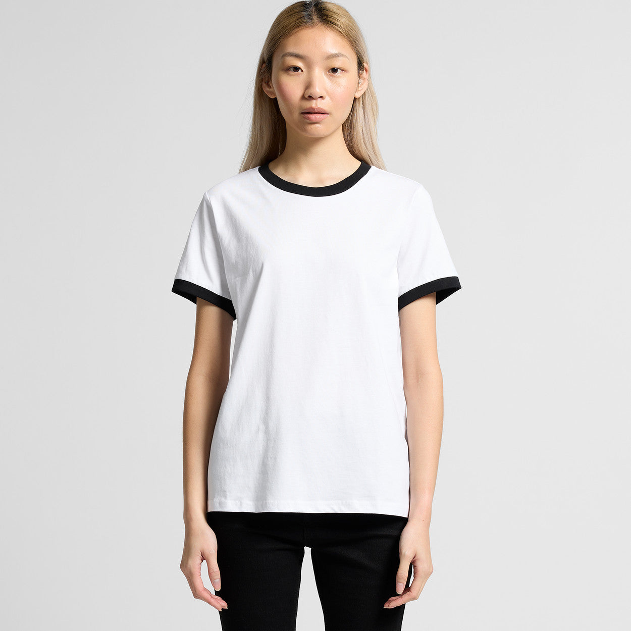 Person wearing a white t-shirt with black ringer sleeves on a plain background